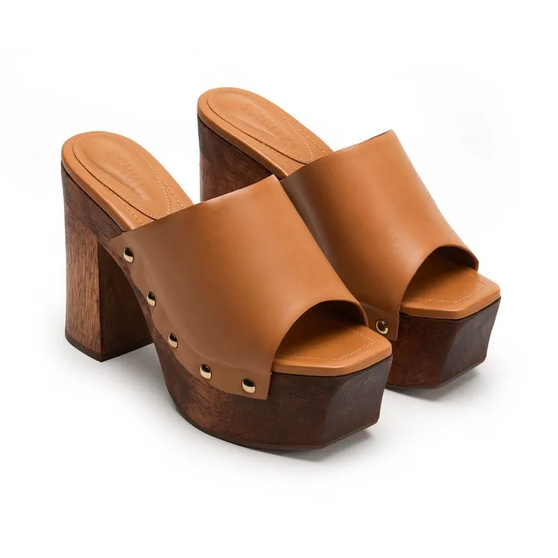 Pair of tan leather platform clog mules on a white background